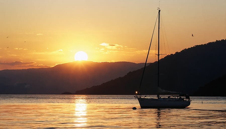 Peaceful sailboat at anchor during golden hour with safety equipment visible